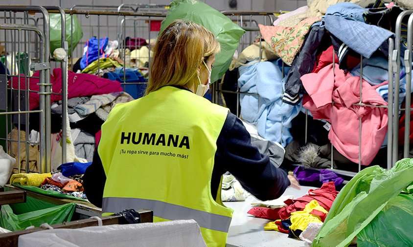 Personal d'Humana classificant peces de roba a la planta que la fundació té a l'Ametlla del Vallès