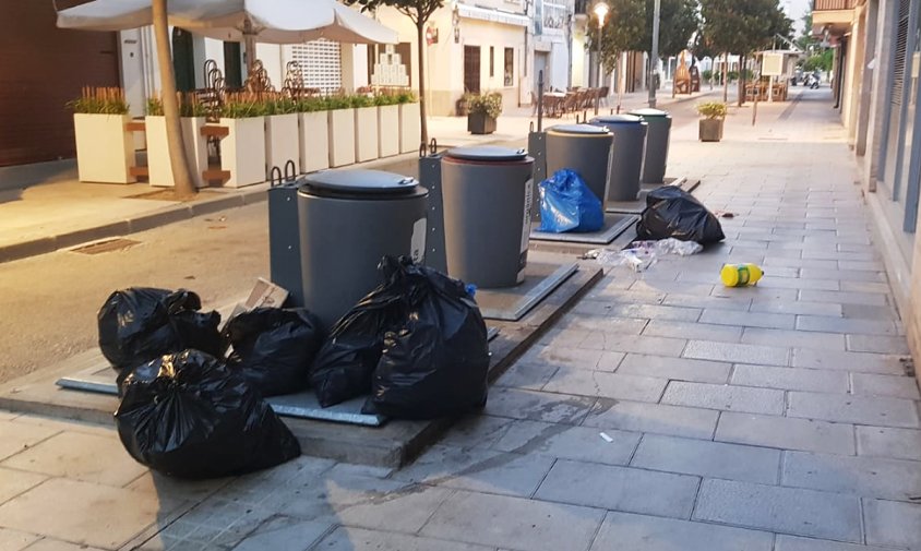 Bosses de brossa amuntegades al voltant d'una bateria de contenidors, al barri del port