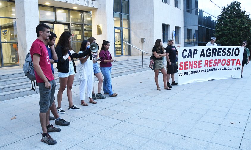 Sis dels joves que van denunciar l'agressió al costat de la pancarta que presidia la concentració, ahir al vespre, a la plaça de l'Ajuntament