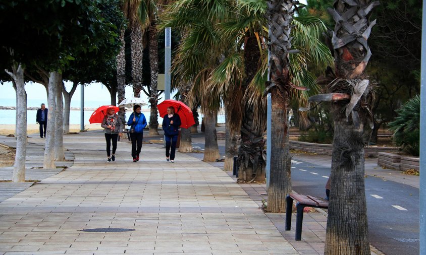 Gent passejant amb paraigües pel passeig de Ponent de Cambrils