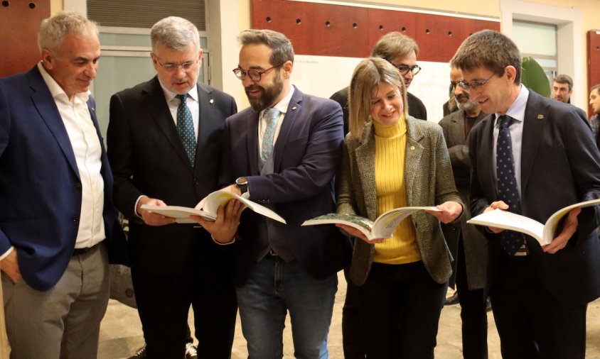 El conseller de Territori, Juli Fernàndez, l'alcalde de Tarragona, l'alcaldessa accidental de Reus, el delegat del Govern a Tarragona i el rector de la URV mirant el llibre sobre les directrius del futur PDU