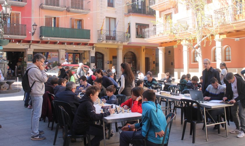 Joves d'entre 5 i 16 anys disputant partides ràpides d'escacs a la plaça de la Vila