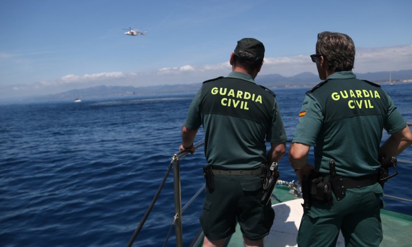 Dos agents de la Guàrdia Civil observant l'helicòpter de Salvament Marítim davant de la costa cambrilenca