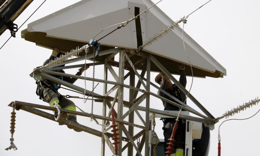 Imatge d'uns operaris de la companyia treballant en una torre elèctrica