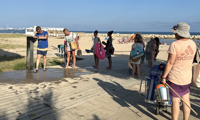 Gent fent cua per rentar-se els peus a la font de la platja de la Llosa