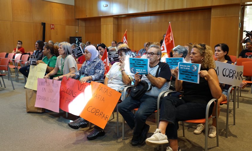 Els treballadors han portat cartells de protesta a la sala de plens