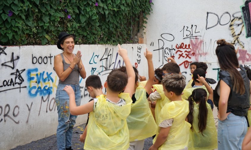 Dera Wells explica als nens i nenes del SADI com hauran de pintar la paret