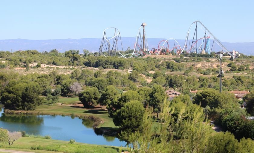 Terrenys del Centre Recreatiu i Turístic (CRT) de Vila-seca i Salou, amb un llac i camp de golf de PortAventura (Lumine) en primer terme, i les atraccions al fons