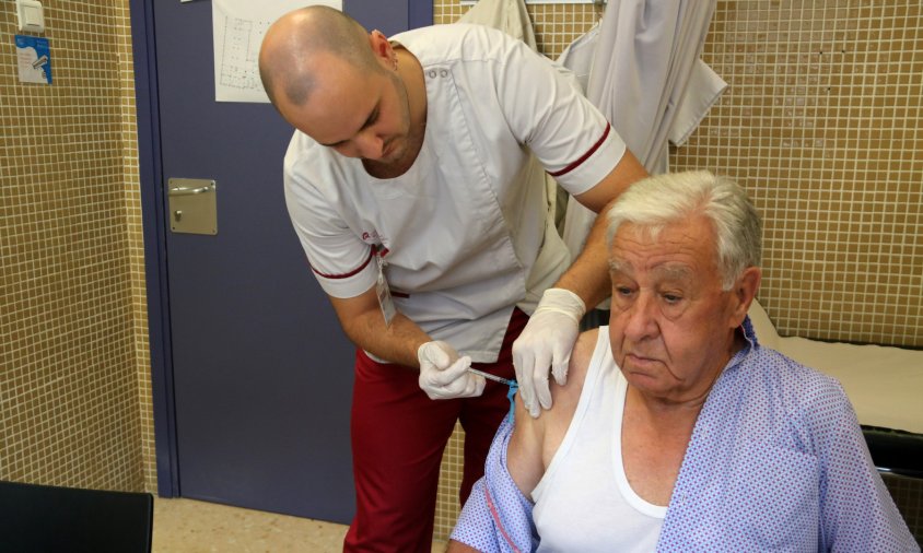 Imatge d'un infermer posant la vacuna de la grip i de la covid a un pacient