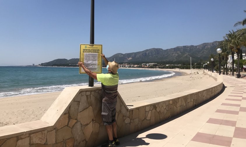 Un operari instal·lant un cartell informatiu a la platja